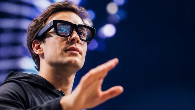 Google AI Glasses product reveal on stage with presenter before audience, featuring futuristic blue and red light effects