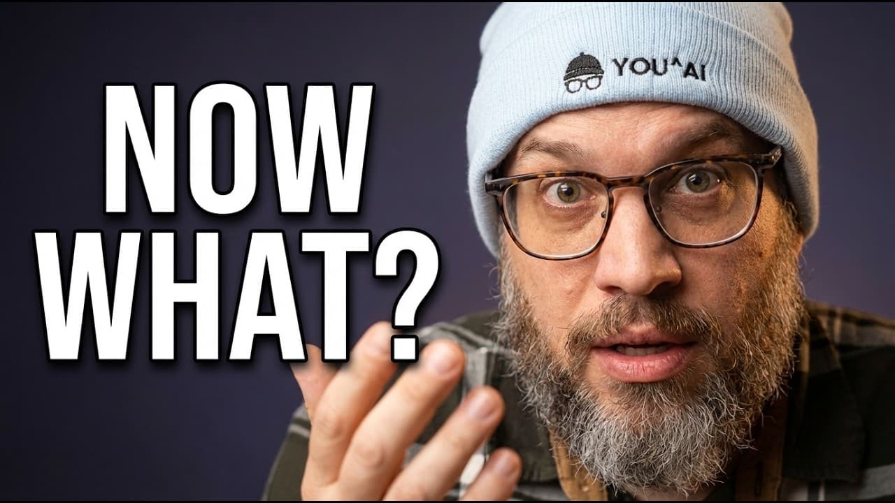 Bearded man wearing glasses and a beanie gestures toward camera with confused expression, text reads "NOW WHAT?
