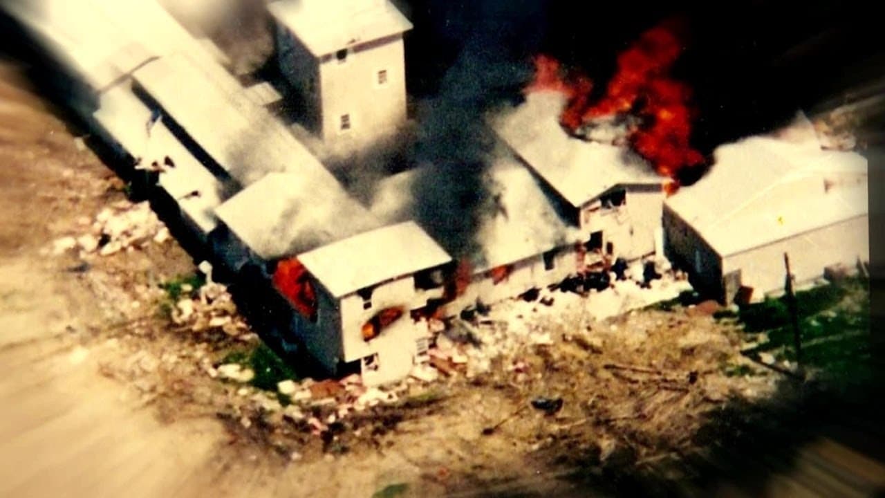 Aerial view of compound buildings with smoke and flames rising from structures during confrontation