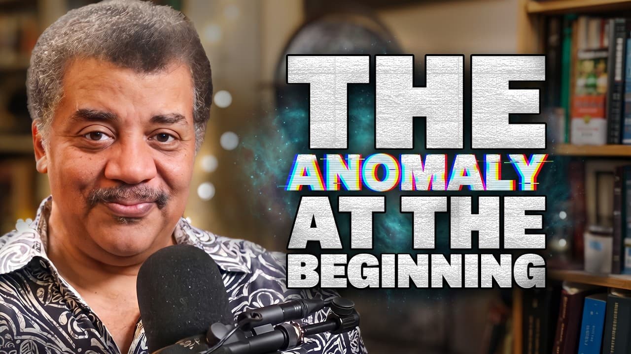 A man with gray hair wearing a patterned shirt speaks into a microphone in front of bookshelves, with bold text reading…