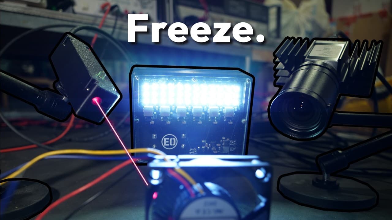 High-tech electronics setup with glowing LED display, camera equipment, and colorful wires illuminated in blue light with…