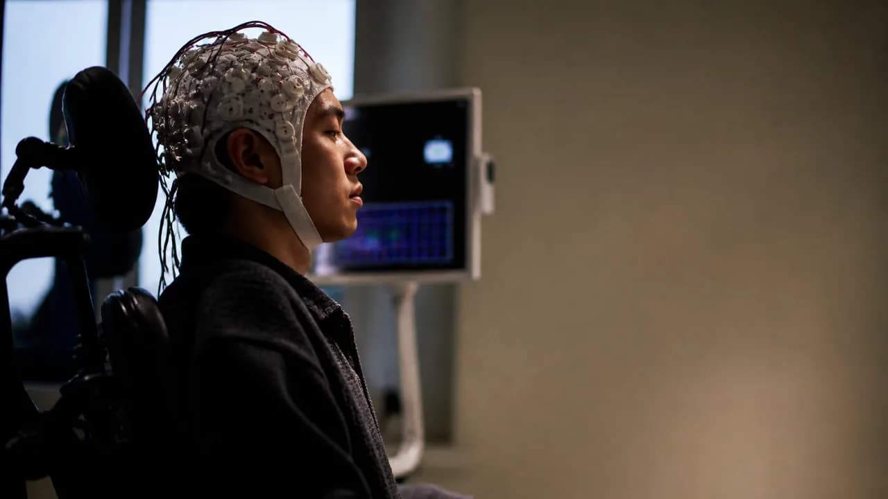 A translucent human head model in profile displays a computer chip implant, with "CONTROLLING COMPUTERS WITH BRAINS" text…