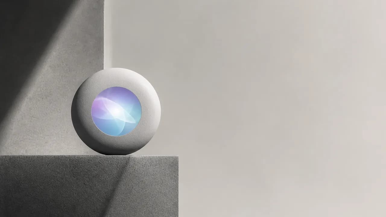 Two hosts with microphones discuss Apple's Siri improvements while a hand holds an iPhone displaying its home screen…